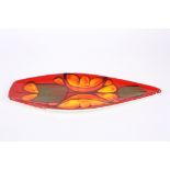 A large Poole pottery leaf shaped dish decorated with flowers on a red ground. Artists monogram to