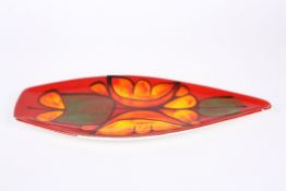 A large Poole pottery leaf shaped dish decorated with flowers on a red ground. Artists monogram to