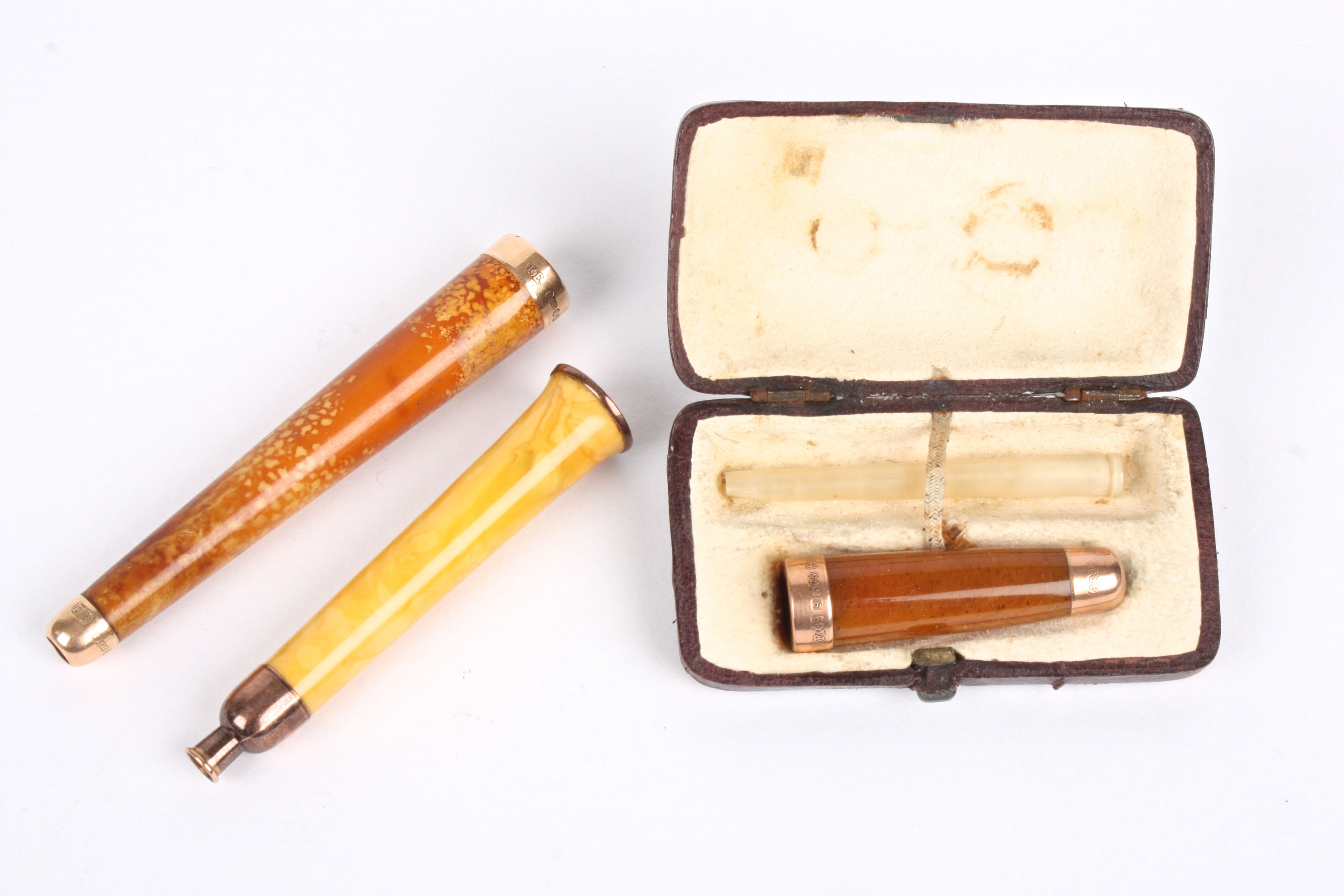 An early 20th century 15ct gold mounted amber coloured cigarette holder together with two other
