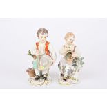 Two early 20th century German porcelain figures of a boy and girl seated holding flowers and