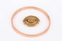 A 9ct gold stiff bangle together with a Victorian yellow metal oval brooch. (2) Bangle 11 grams.