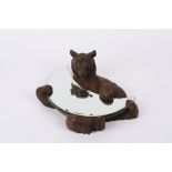 A 19th century German or Swiss carved Black forest wall mirror carved as a bear holding a crescent