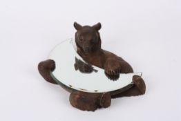 A 19th century German or Swiss carved Black forest wall mirror carved as a bear holding a crescent