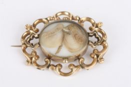 A Victorian scroll memorial brooch of open pierced design with central hair and pearl detail