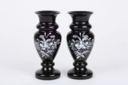 A pair of Victorian Amethyst glass vases decorated with white enamel flowers. 16.5 cm high.