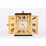 A Must de Cartier gilt metal travel clock with engraved sunburst decoration, the two doors opening