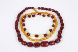 A large opaque amber graduated barrel shaped bead necklace, another short cherry amber and satin