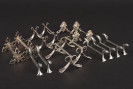 A collection of pairs of silver plated knife rests including Art Nouveau style knife rests.