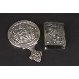 A small Dutch silver repoussé pocket hand mirror decorated with a scene of figures merrymaking,