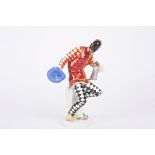 A 20th century Meissen porcelain figure of a harlequin holding jug and hat and seated on a