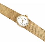 A ladies 9ct gold Tissot watch the small oval silvered dial with baton numerals, on a 9ct gold