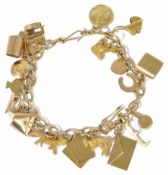 A delicate 9ct gold charm bracelet hung with a variety of charms including a Yale key, wishing well,