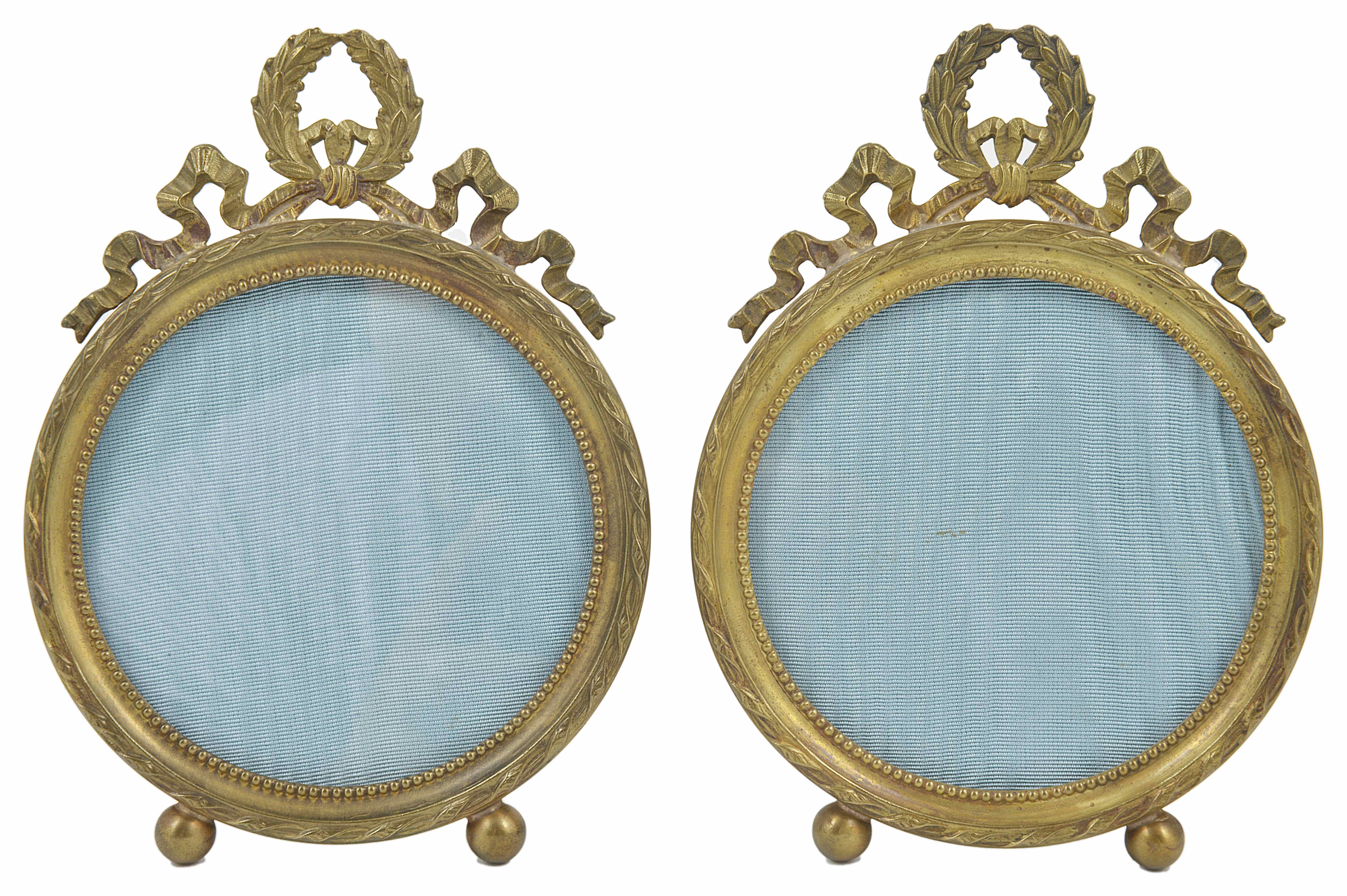 A pair of gilt metal Continental photo frames of circular form, raised on ball feet, with ribbon and