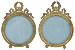 A pair of gilt metal Continental photo frames of circular form, raised on ball feet, with ribbon and