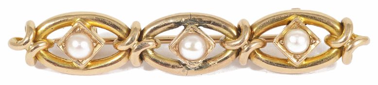 An Edwardian half pearl set bar brooch of three section scroll design each section with central