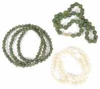 A row of lightly graduated cultured pearls and two single row green hardstone necklaces Condition: