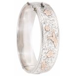 A hollow silver hinged bangle with gold overlay and scroll engraved decoration. Condition: Slight