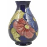 A Walter Moorcroft vase decorated with peonies and leaves against a cobalt blue background, signed