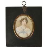 An early 19th century miniature on ivory of a young girl wearing a blue and white dress with