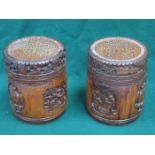 PAIR OF HEAVILY CARVED TREEN AND BAMBOO STORAGE POTS WITH COVERS (AT FAULT)