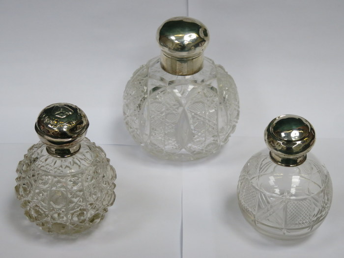 THREE VARIOUS SILVER TOPPED GLASS PERFUME DECANTERS