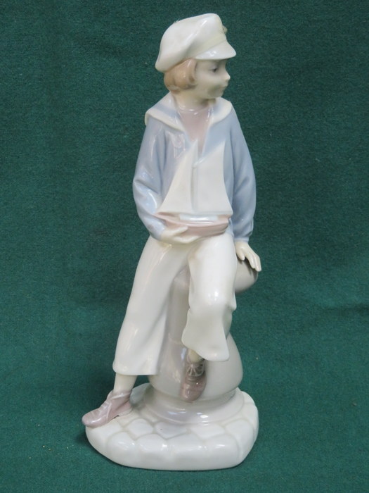 LLADRO GLAZED CERAMIC FIGURE OF A SEATED BOY WITH BOAT.