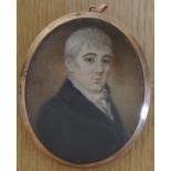 A framed portrait miniature portrait of a gentleman wearing a black jacket, in an enclosed gold