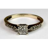 A 9ct gold diamond solitaire ring with diamond set shoulders (N).