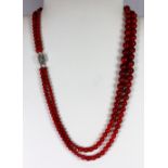 A two row graduated necklace of coral beads on a white metal clasp.