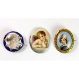 Two 19th century hand painted porcelain portrait brooches and a hand painted porcelain cherub