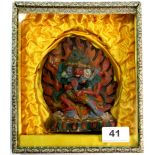 A cased mid 20th century Tibetan painted clay pilgrims tablet of a tantric Deity in a purpose made