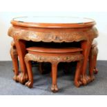 An ornately carved Chinese teak and glass tea table and four stools, Dia. 76cm, H. 53cm.