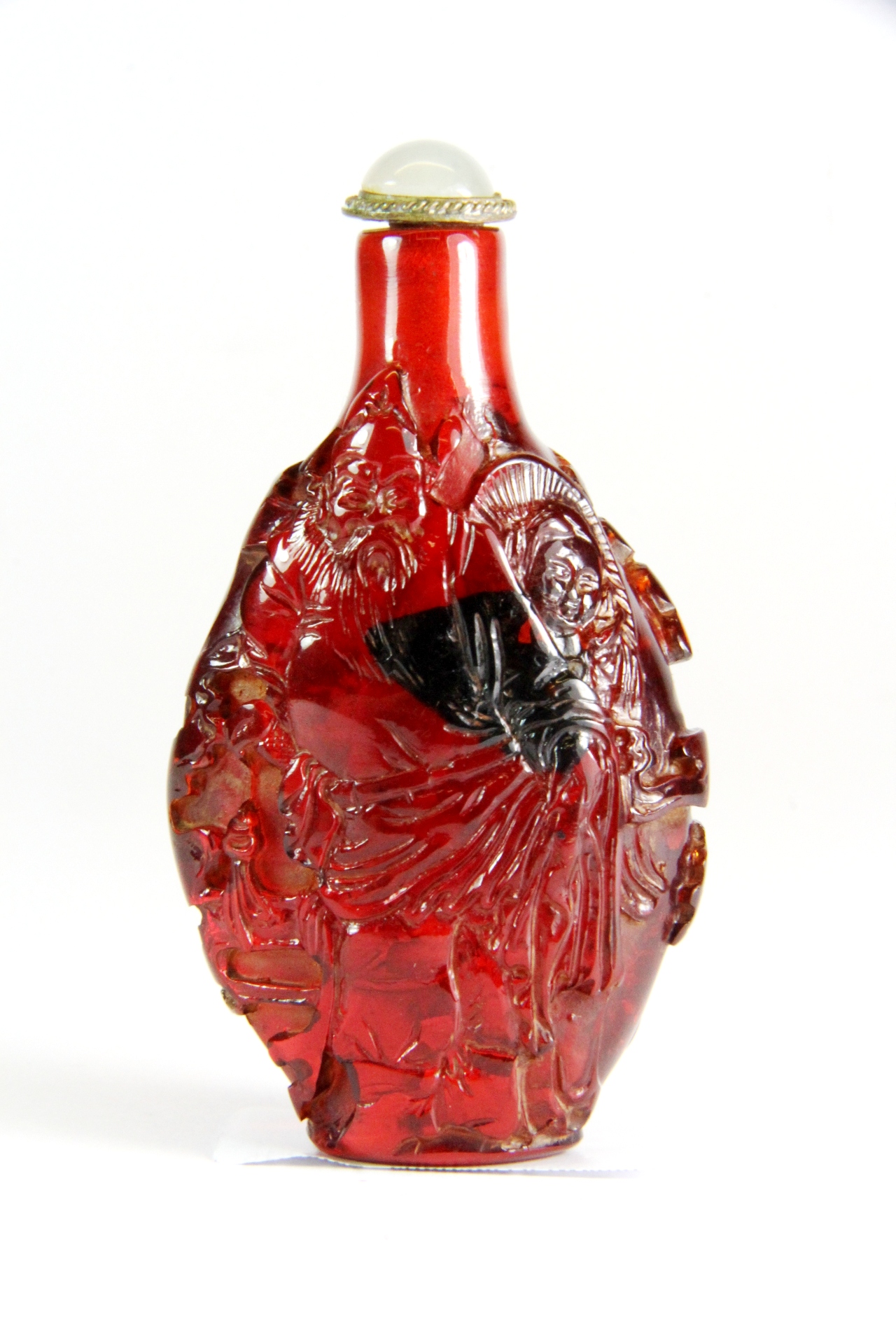 A Chinese carved red Peking glass snuff bottle of an Emperor in a landscape, H. 8cm.
