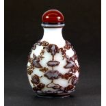 A finely carved Chinese three layer Peking glass snuff bottle with cornelian stopper, H. 6.5cm.