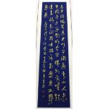 A Chinese silk mounted calligraphy scroll in gold ink on a blue painted background, W. 42cm.