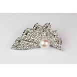 A white metal brooch set with a cultured pearl and cubic zirconia.