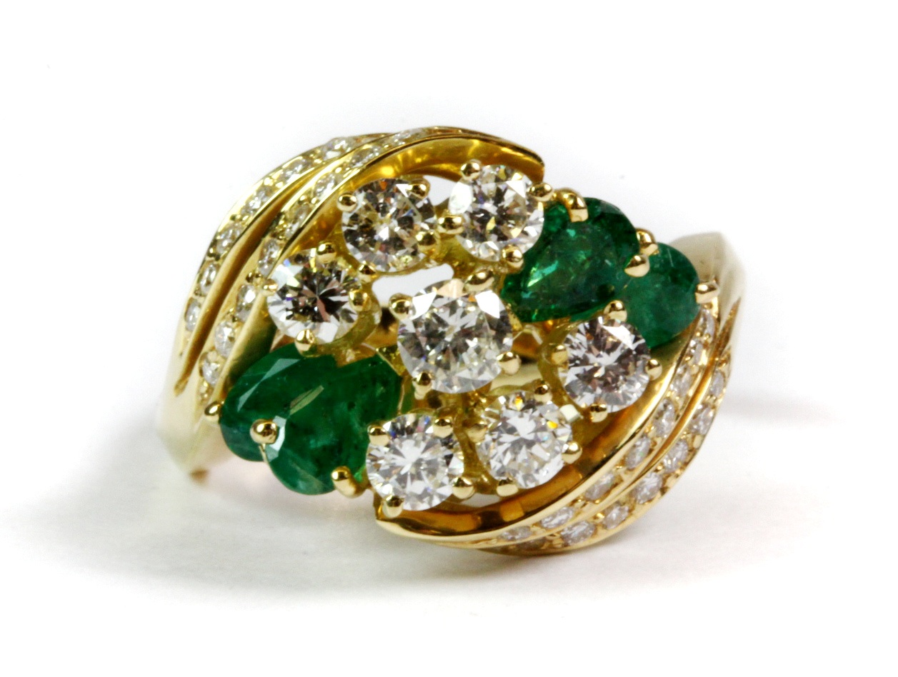 A matching 18ct yellow gold (tested) ring set with pear cut emeralds and brilliant cut diamonds (