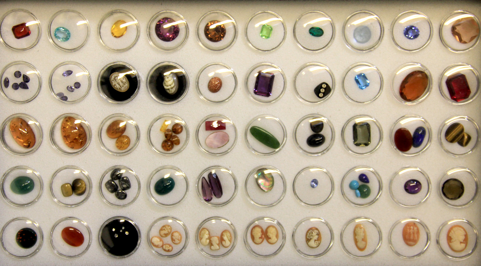 A box of containing over 50 unmounted gemstones including diamonds, sapphires, etc.