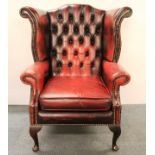 An ox blood leather upholstered wing armchair.