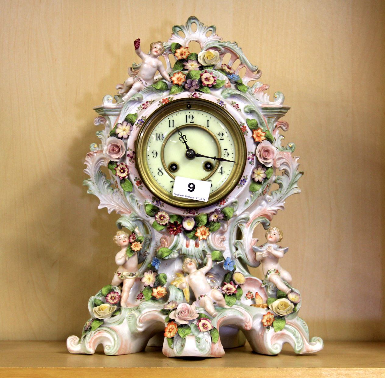 A 19th century German porcelain cased clock decorated with bocage and putti, H. 37cm.