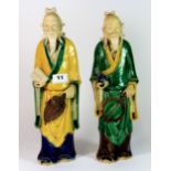 A pair of mid 20th century Chinese pottery figures of bearded gentlemen, each with brightly coloured