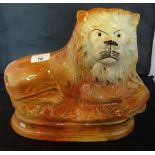 A Staffordshire figure of a recumbent lion on oval base with a lustre and gilt finish (25cm).