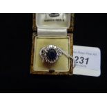 An 18ct white gold ring set with large central sapphire and circled by twelve diamonds.