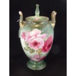 A late Victorian/Edwardian twin handled jar and cover, having hand painted roses on a green ground,