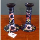 A pair of Moorcroft Pansy pattern candlesticks on a blue ground,