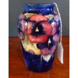 A Moorcroft Pansy pattern vase on a blue ground, impressed and painted WM signature to base (16cm).