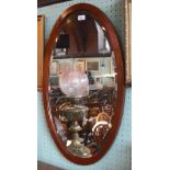 An Edwardian mahogany framed oval wall mirror, with bevelled plate.