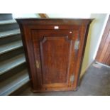 A George III oak hanging corner cupboard, with fielded panel door and brass furniture.