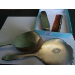 A silver back hand mirror, together with two brushes and a comb.