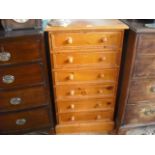 A contemporary pine narrow chest of six drawers, each with knop handles on plinth.